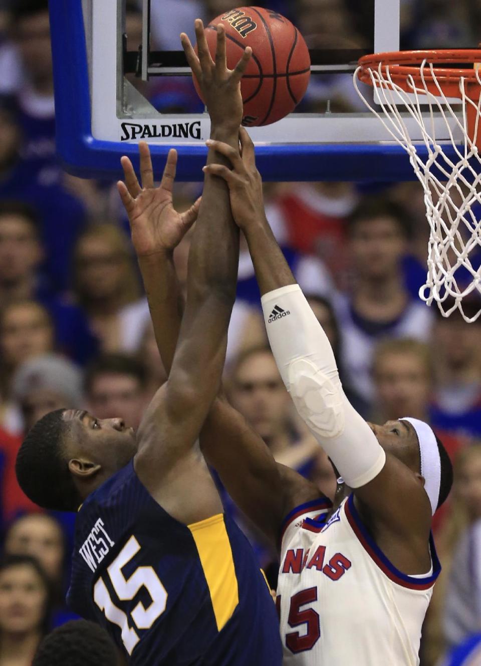 West Virginia forward Lamont West, left, is fouled by Kansas forward Carlton Bragg Jr., during the first half of an NCAA college basketball game in Lawrence, Kan., Monday, Feb. 13, 2017. (AP Photo/Orlin Wagner)