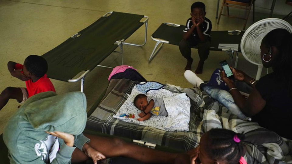 A family sits on cots with other residents inside a church that was opened up as a shelter as they wait out Hurricane Dorian in Freeport on Grand Bahama, Bahamas. Source: AP