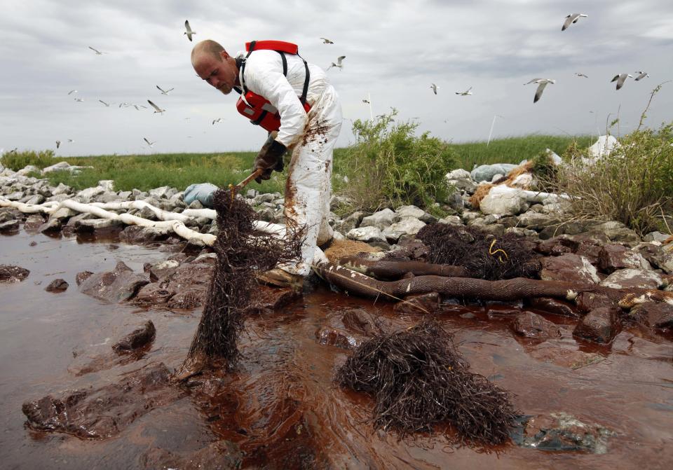 FILE- In this June 4, 2010 file photo, a worker picks up blobs of oil with absorbent snare on Queen Bess Island at the mouth of Barataria Bay near the Gulf of Mexico in Plaquemines Parish, La. BP and five Gulf states announced a record $18.7 billion settlement Thursday, July 2, 2015, that resolves years of legal fighting over the environmental and economic damage done by the energy giant’s oil spill in 2010. (AP Photo/Gerald Herbert, File)