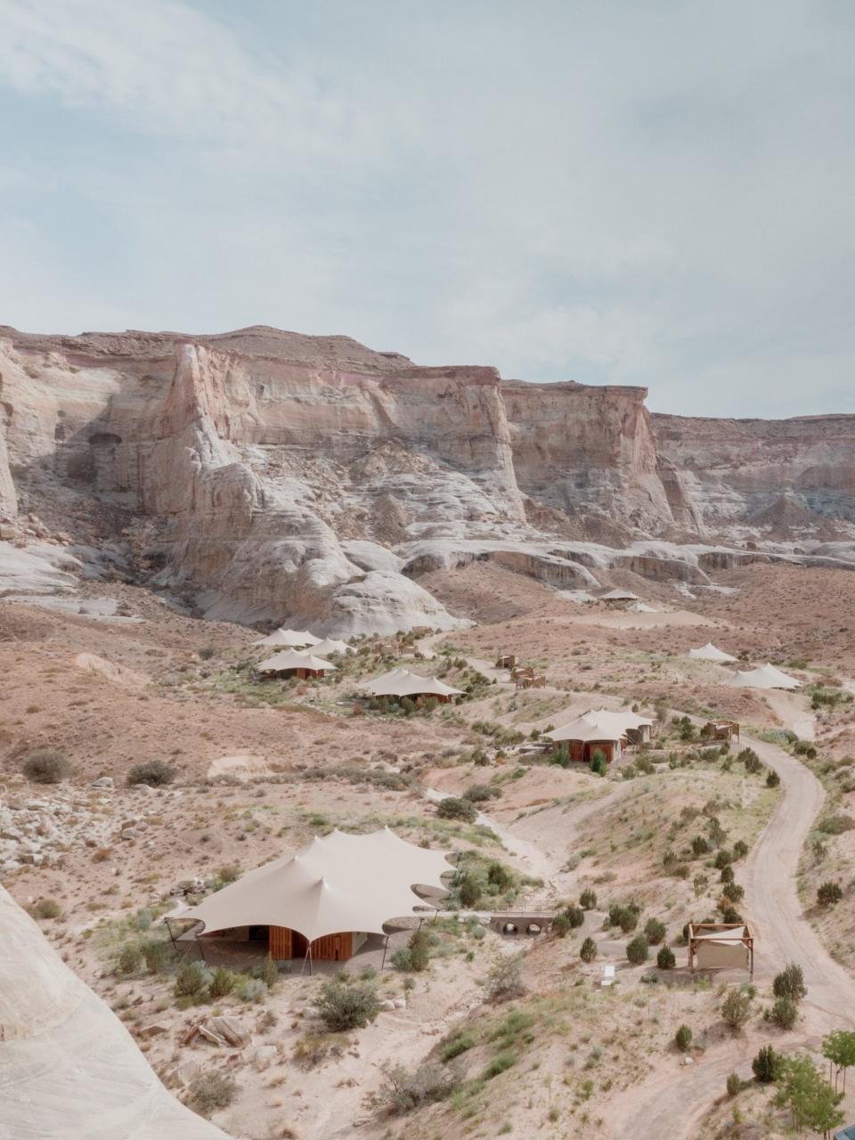 Tents sit in a desert with cliffs, blending into the scenery.