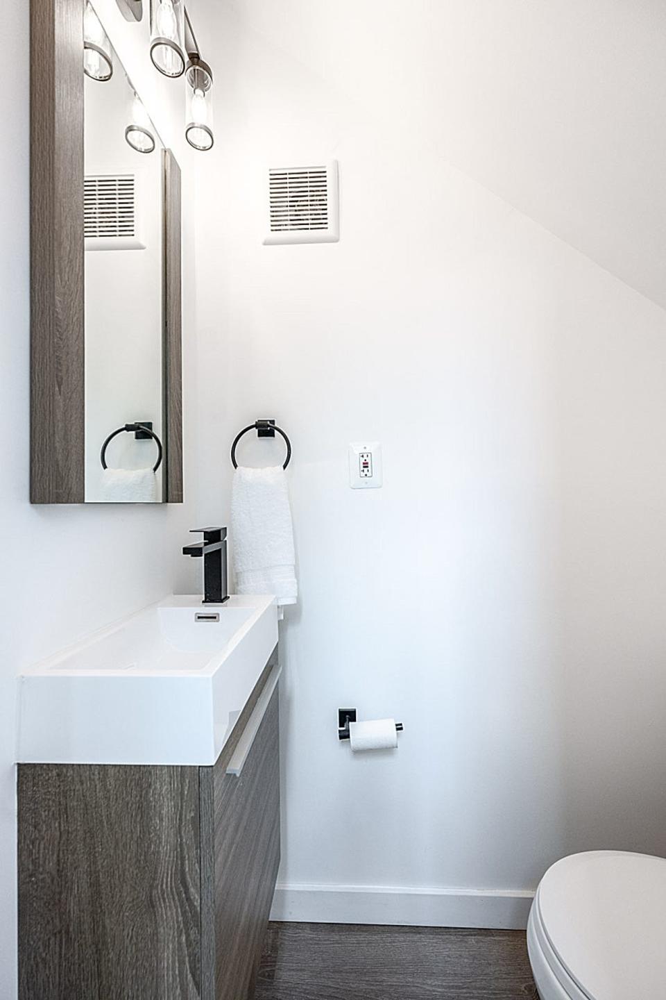 A powder room under the stairs of a skinny home.