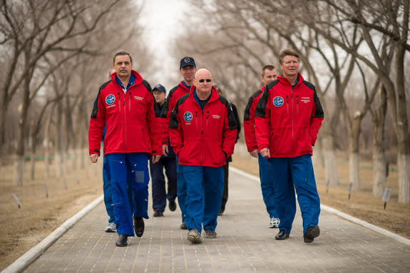 NASA astronaut Scott Kelly (center) and Russian cosmonauts Gennady Padalka (right) and Mikhail Kornienko of the Russian Federal Space Agency Roscosmos walk along the Avenue of the Cosmonauts, where two long rows of trees are each marked with th