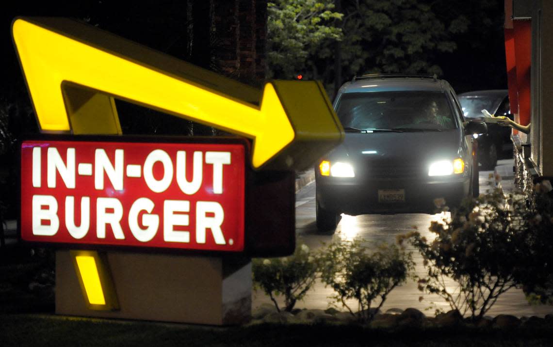 A customer receives an order from the drive-thru at an In-N-Out Burger.