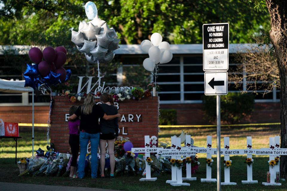 May 26, 2022: A family pays their respects next to crosses bearing the names of Tuesday's shooting victims at Robb Elementary School in Uvalde, Texas.