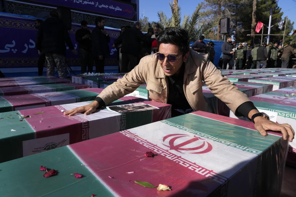 A man mourns over the flag-draped coffin of his sister who was killed in Wednesday's bomb explosion, during the victims funeral ceremony in the city of Kerman about 510 miles (820 km) southeast of the capital Tehran, Iran, Friday, Jan. 5, 2024. Iran on Friday mourned those slain in an Islamic State group-claimed suicide bombing targeting a commemoration for a general slain in a U.S. drone strike in 2020. (AP Photo/Vahid Salemi)