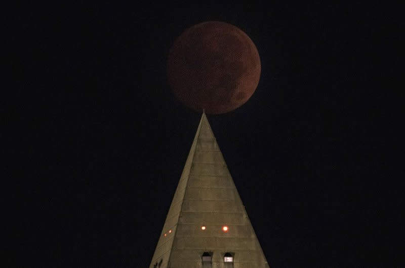 The moon darkens and is reddish during a total lunar eclipse in the sky next to the Washington Monument in Washington in November 2022. File Photo by Pat Benic/UPI
