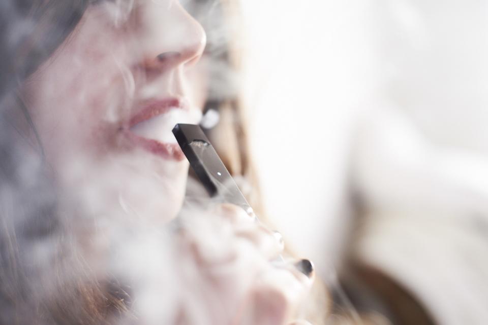 A woman smokes a Juul, the leading e-cigarette that has grown to become the FDA’s biggest target.