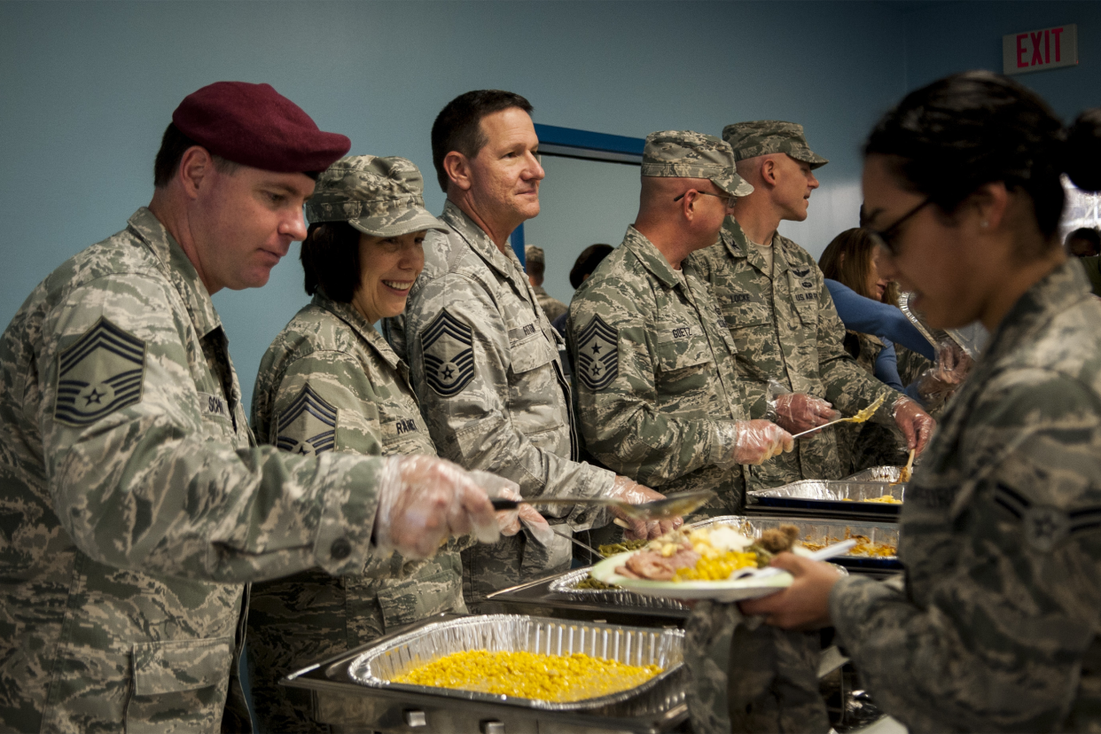Senior NCOs and officers serve food to Airmen during the Thanksgiving luncheon