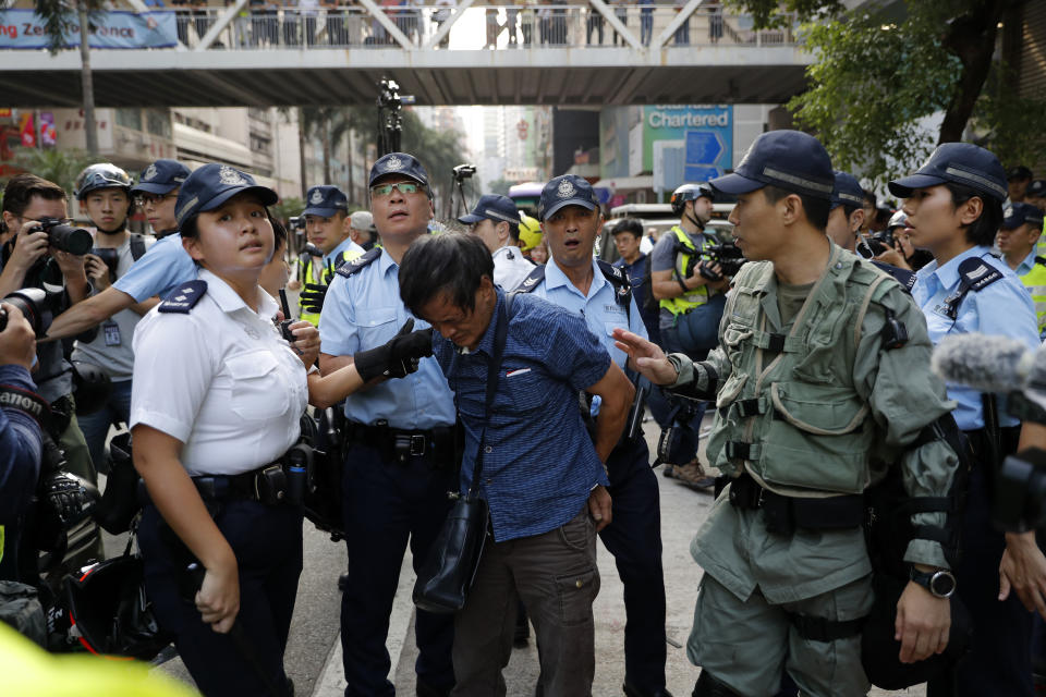 Police detain a pro-China protester as they break up anti-government protesters and pro-China supporters as they clash in Wang Chai district, Tuesday, Oct. 1, 2019, in Hong Kong while the celebration of the People's Republic's 70th anniversary is taking place in Beijing. Police are warning of the potential for protesters to engage in violence "one step closer to terrorism" during this week's National Day events, an assertion ridiculed by activists as propaganda meant to scare people from taking to the streets. (AP Photo/Vincent Thian)