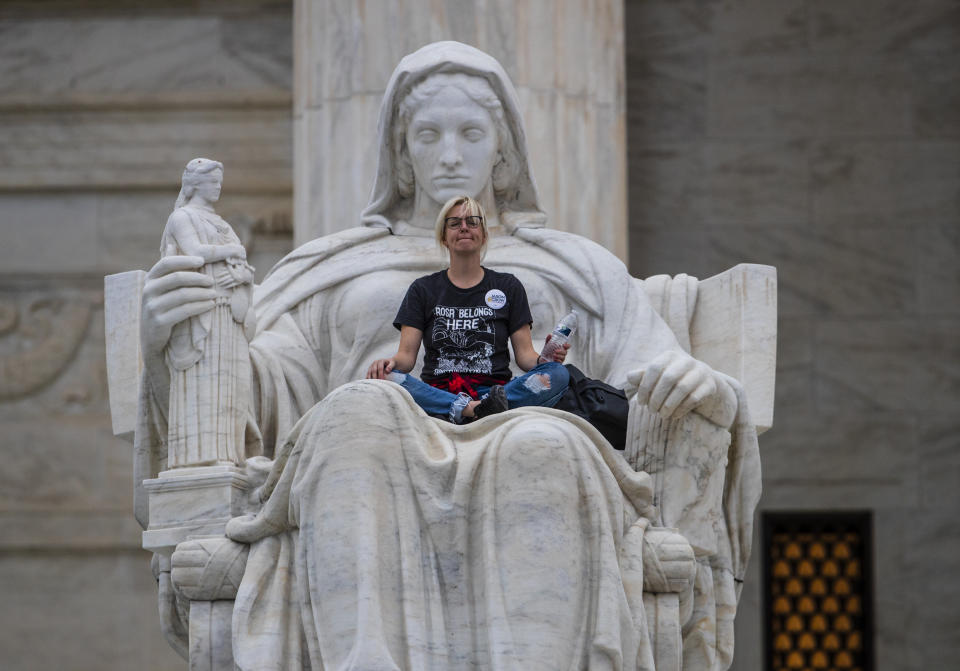 Jessica Campbell-Swanson, an activist from Denver, sits in the lap of a sculpture known as the Statue of Contemplation of Justice on the steps of the Supreme Court Building where she and others protested the confirmation of Brett Kavanaugh as the high court's newest justice, in Washington, Saturday, Oct. 6, 2018. Kavanaugh took the oath inside the building after the bitterly polarized U.S. Senate narrowly confirmed him, delivering an election-season triumph to President Donald Trump that could swing the court rightward for a generation. (AP Photo/J. Scott Applewhite)