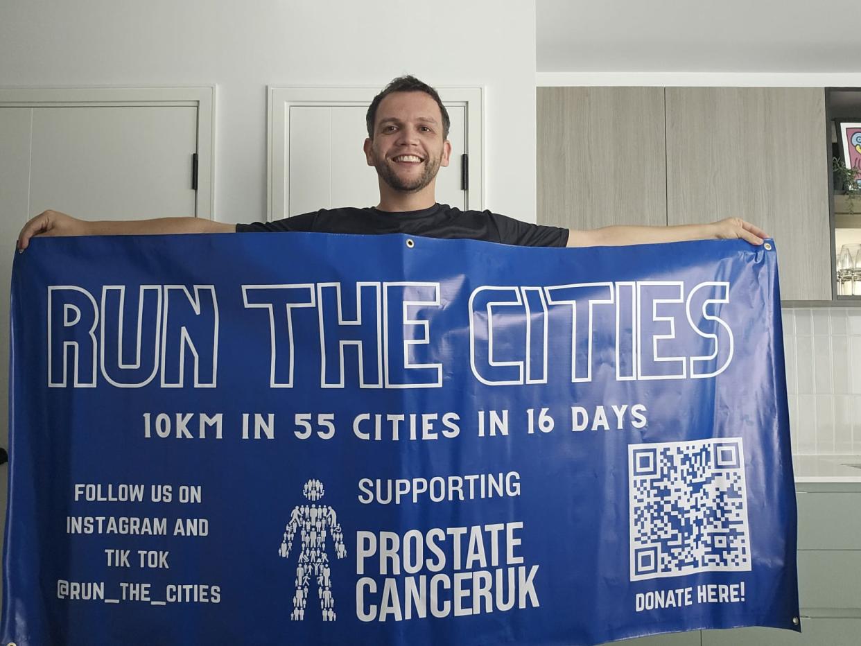 Man smiling and holding a banner that says Run The Cities, a challenge to raise money for Prostate Cancer UK