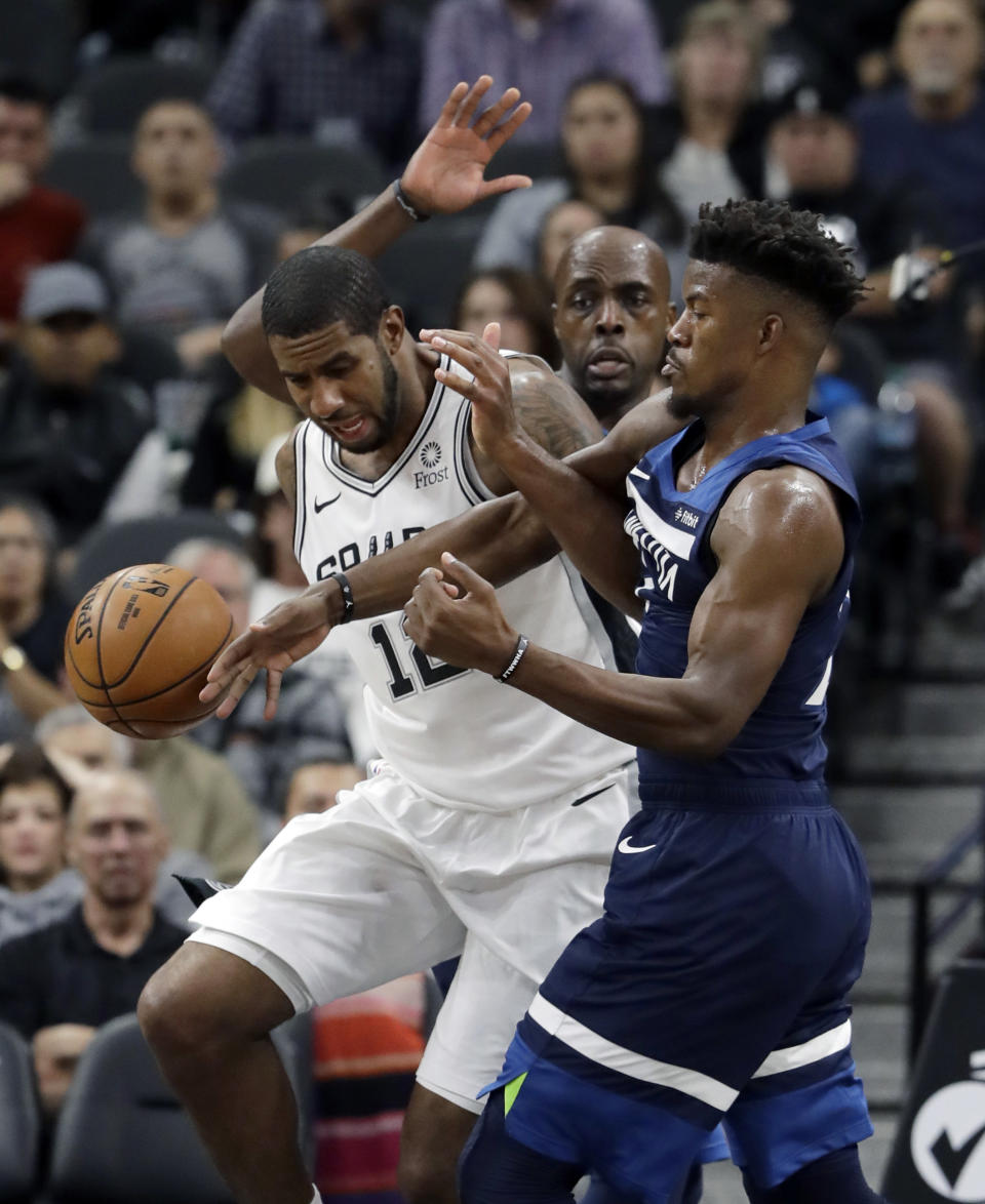 San Antonio Spurs forward LaMarcus Aldridge (12) and Minnesota Timberwolves guard Jimmy Butler, right, scramble for a rebound during the first half of an NBA basketball game, Wednesday, Oct. 17, 2018, in San Antonio. (AP Photo/Eric Gay)