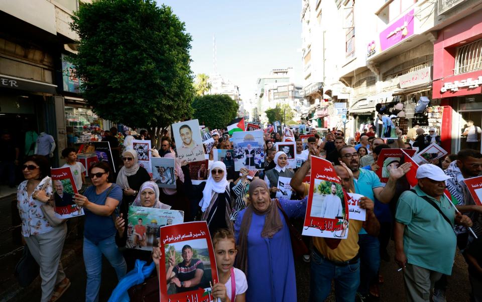 Palestinians holding images of relatives held in Israeli jails protest at the Duwar al-Manara in the Israeli-occupied West Bank