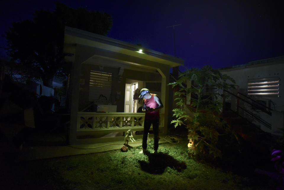 In this Sept. 7, 2018 photo, 56-year-old dialysis patient Elias Salgado plays with his dog Farruko in his front yard in Vieques, Puerto Rico, the night before traveling by plane to the Puerto Rican mainland. Salgado makes the trip three times a week for dialysis treatments. A year has passed since the Category 4 shuttered the only dialysis treatment center in Vieques. (AP Photo/Carlos Giusti)