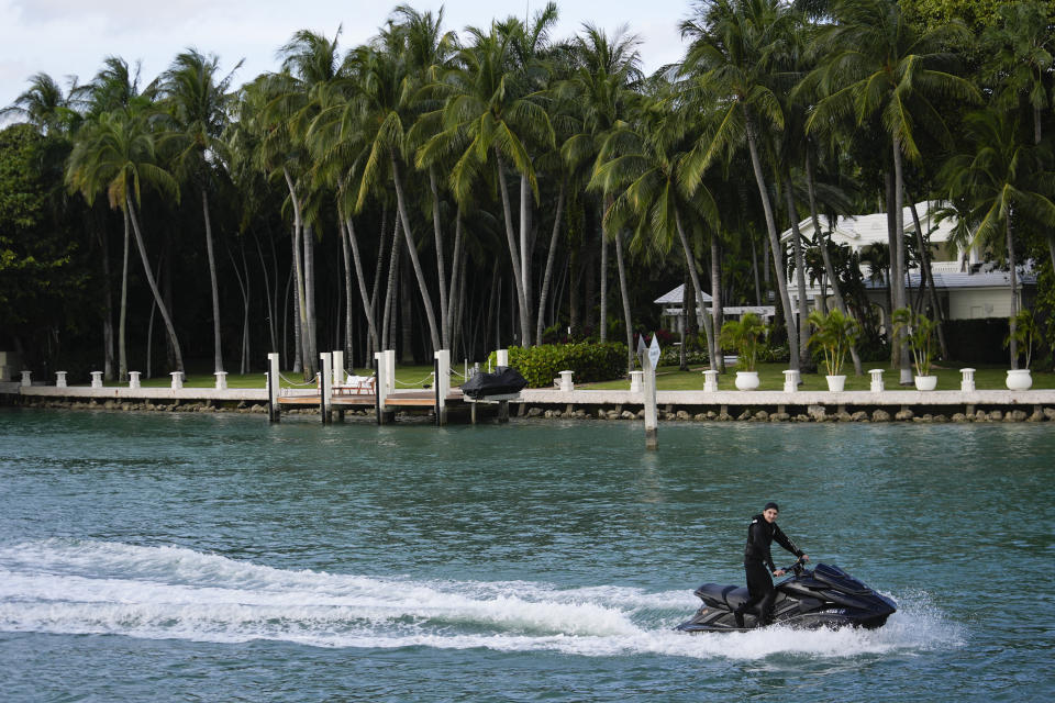 A man on a personal watercraft rides past a property belonging to rapper Sean "Diddy" Combs, as it was being raided by federal law enforcement agents, Monday, March 25, 2024, on Star Island in Miami Beach, Fla. Two properties belonging to Combs in Los Angeles and Miami were searched by federal Homeland Security Investigations agents and other law enforcement as part of an ongoing sex trafficking investigation by federal authorities in New York, two officials told The Associated Press. (AP Photo/Rebecca Blackwell)