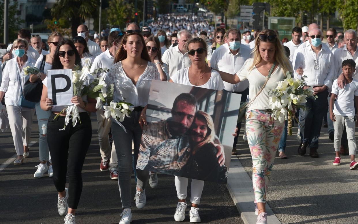 Veronique Monguillot (centre), wife of bus driver Philippe Monguillot, holds a picture of her husband during a white march in Bayonne, France - IROZ GAIZKA/AFP