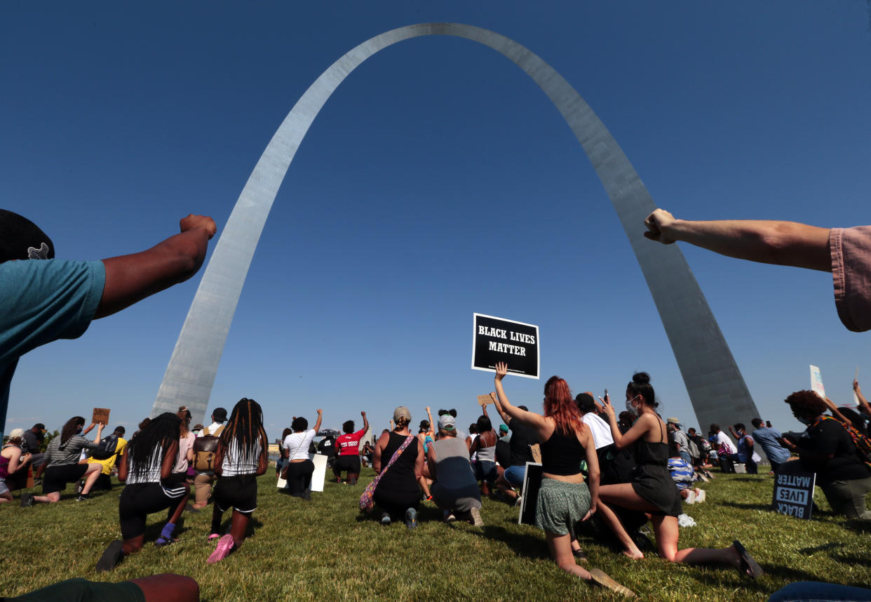 Participants raise their fists in solidarity during a moment of silence for those lost to police brutality, under the Gateway Arch during a rally in St. Louis on Sunday, June 14, 2020. (Robert Cohen/St. Louis Post-Dispatch via AP)