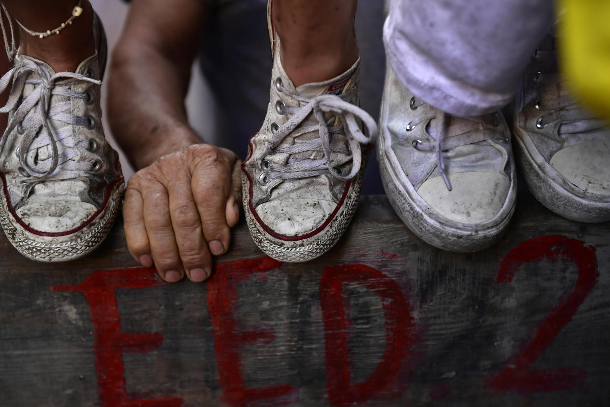 People stand on wooden barriers to watch the running of the bulls on the first day at the San Fermin Festival in Pamplona, northern Spain, Thursday, July 7, 2022. Revelers from around the world flock to Pamplona every year for nine days of uninterrupted partying in Pamplona's famed running of the bulls festival which was suspended for the past two years because of the coronavirus pandemic. (AP Photo/Alvaro Barrientos)