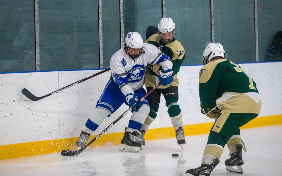 St. Mary Catholic Central's Daniel Neubauer (5) and Will Craiger (7) fight for the puck with Tyler Watson of Gibraltar Carlson Tuesday night. Carlson won 8-0.