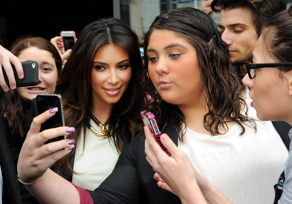 File - In this Friday, Sept. 21, 2012 file photo Kim Kardashian, left, is surrounded by her fans who are attempting to have their photographs taken with her as she leaves a radio station in Melbourne, Australia. "Selfie" the smartphone self-portrait has been declared word of the year for 2013 by Britain's Oxford University Press. (AP Photo/Mal Fairclough, File)