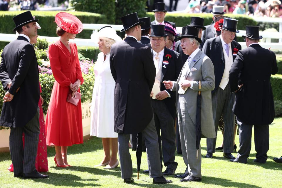 Charles, Camilla, Kate Middleton, and William standing with a group of people on a lawn outside.