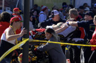 A woman is rushed to an ambulance following a shooting at the Kansas City Chiefs NFL football Super Bowl celebration in Kansas City, Mo., Wednesday, Feb. 14, 2024. Multiple people were injured, a fire official said. (AP Photo/Reed Hoffmann)