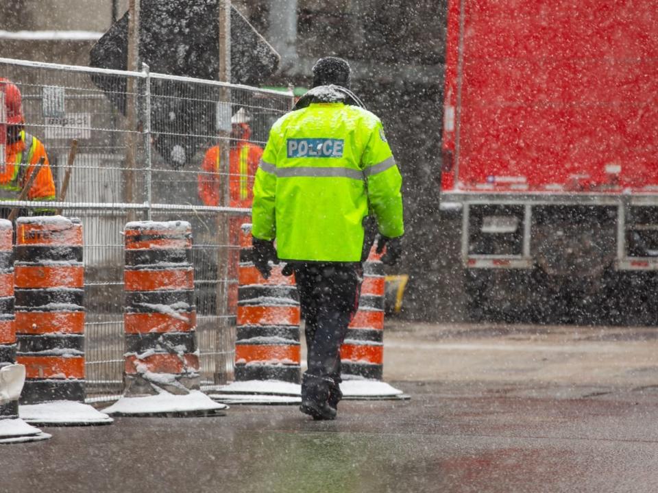 A police officer at Front and John streets as snow falls in Toronto on March 10, 2023. (Michael Wilson/CBC - image credit)