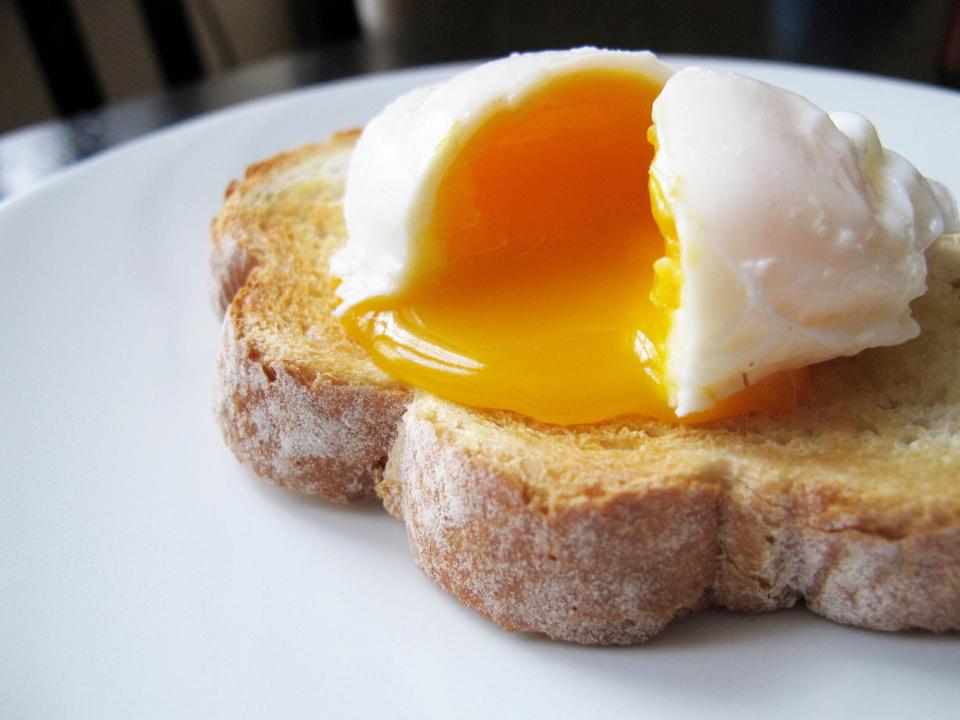 A perfect poached egg oozes yolk onto a piece of toast