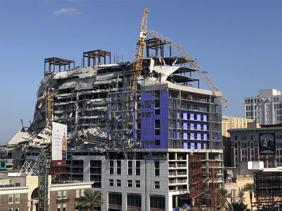 A large crane appears to dangle atop the partially collapsed Hard Rock Hotel after officials set off explosions to topple two cranes on Sunday, Oct. 20, 2019, in New Orleans. (AP Photo/Rebecca Santana)