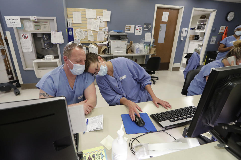 Nurses Jennifer Schofield, left, and David Morgan lean into each other as they sit at a nurses' station in the COVID-19 Intensive Care Unit at Harborview Medical Center, Friday, May 8, 2020, in Seattle. Data from COVID-19 projection models show that the rate of infection is increasing in Washington state, Gov. Jay Inslee said Friday, as he urged people to follow his measured approach to slowly reopening the state from his stay-at-home restrictions. (AP Photo/Elaine Thompson)