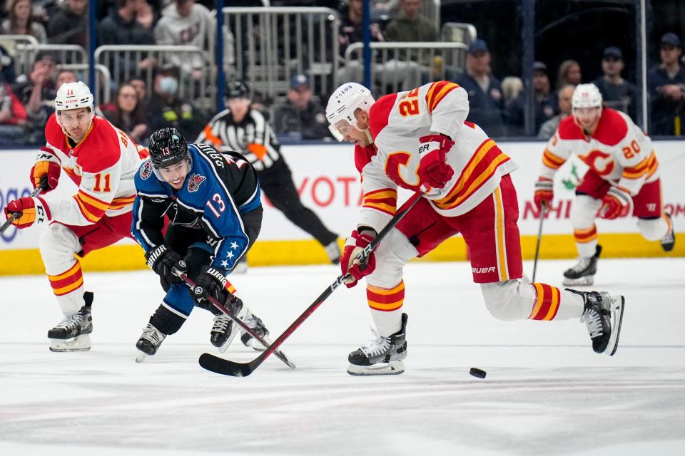 Dec 9, 2022; Columbus, Ohio, United States;  Columbus Blue Jackets left wing Johnny Gaudreau (13) fights for control of the puck with Calgary Flames center Trevor Lewis (22) during the first period of the NHL hockey game between the Columbus Blue Jackets and the Calgary Flames at Nationwide Arena on Friday night. Mandatory Credit: Joseph Scheller-The Columbus Dispatch