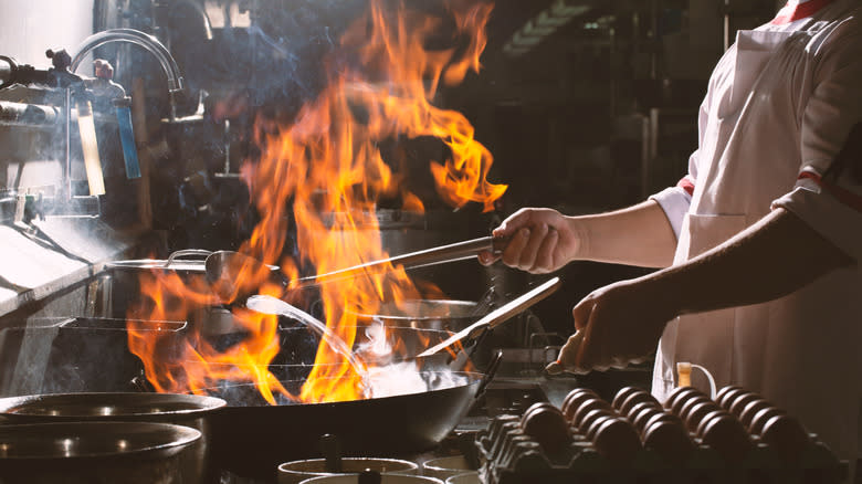 chef cooking in wok with flames