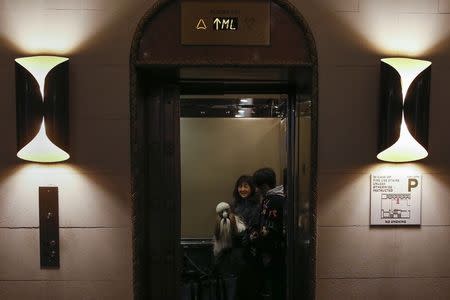 A woman holds a dog inside the elevator of the Affinia Hotel before the upcoming 139th Annual Westminster Kennel Club Dog Show in New York February 13, 2015. REUTERS/Shannon Stapleton