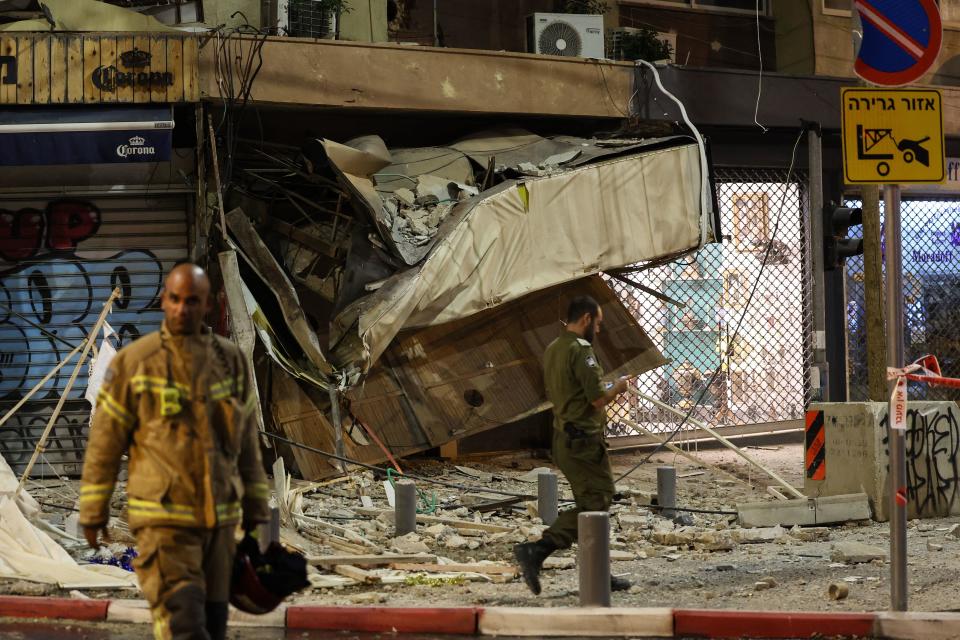 A rescue worker walks near a damaged shop in Tel Aviv after it was hit by a rocket fired by Palestinian militants from the Gaza Strip on Oct. 7, 2023.  / Credit: JACK GUEZ/AFP via Getty Images