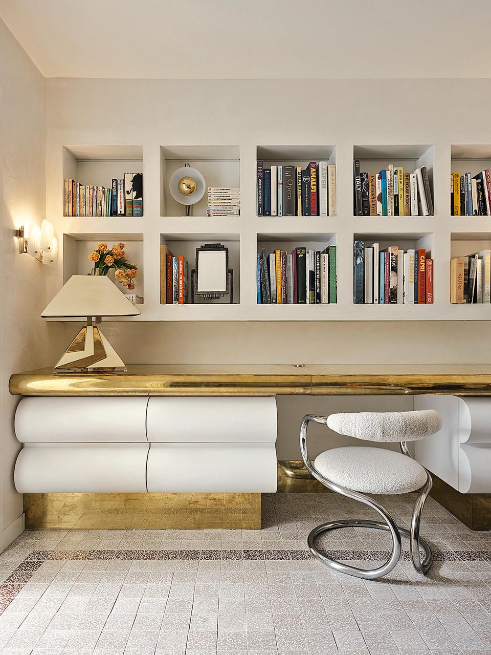 A bookshelf in beige, with metallic gold touches in the room