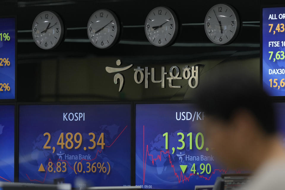 A currency trader walks by the screens showing the Korea Composite Stock Price Index (KOSPI), left, and the foreign exchange rate between U.S. dollar and South Korean won at a foreign exchange dealing room in Seoul, South Korea, Wednesday, April 5, 2023. Asian shares were trading mixed Wednesday following a decline on Wall Street after reports on the U.S. economy came in weaker than expected. (AP Photo/Lee Jin-man)