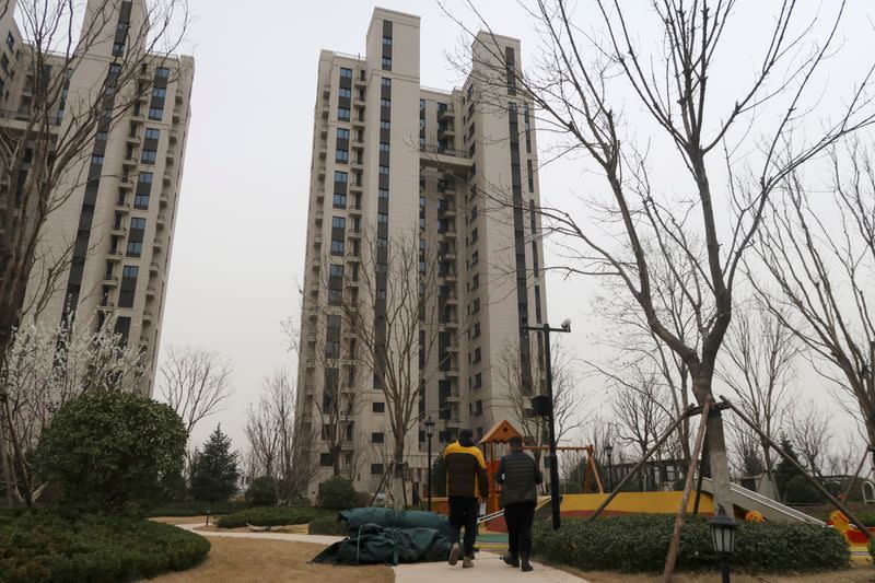 People walk inside the apartment compound Taoyuan Xindu Kongquecheng developed by China Fortune Land Development, in Zhuozhou