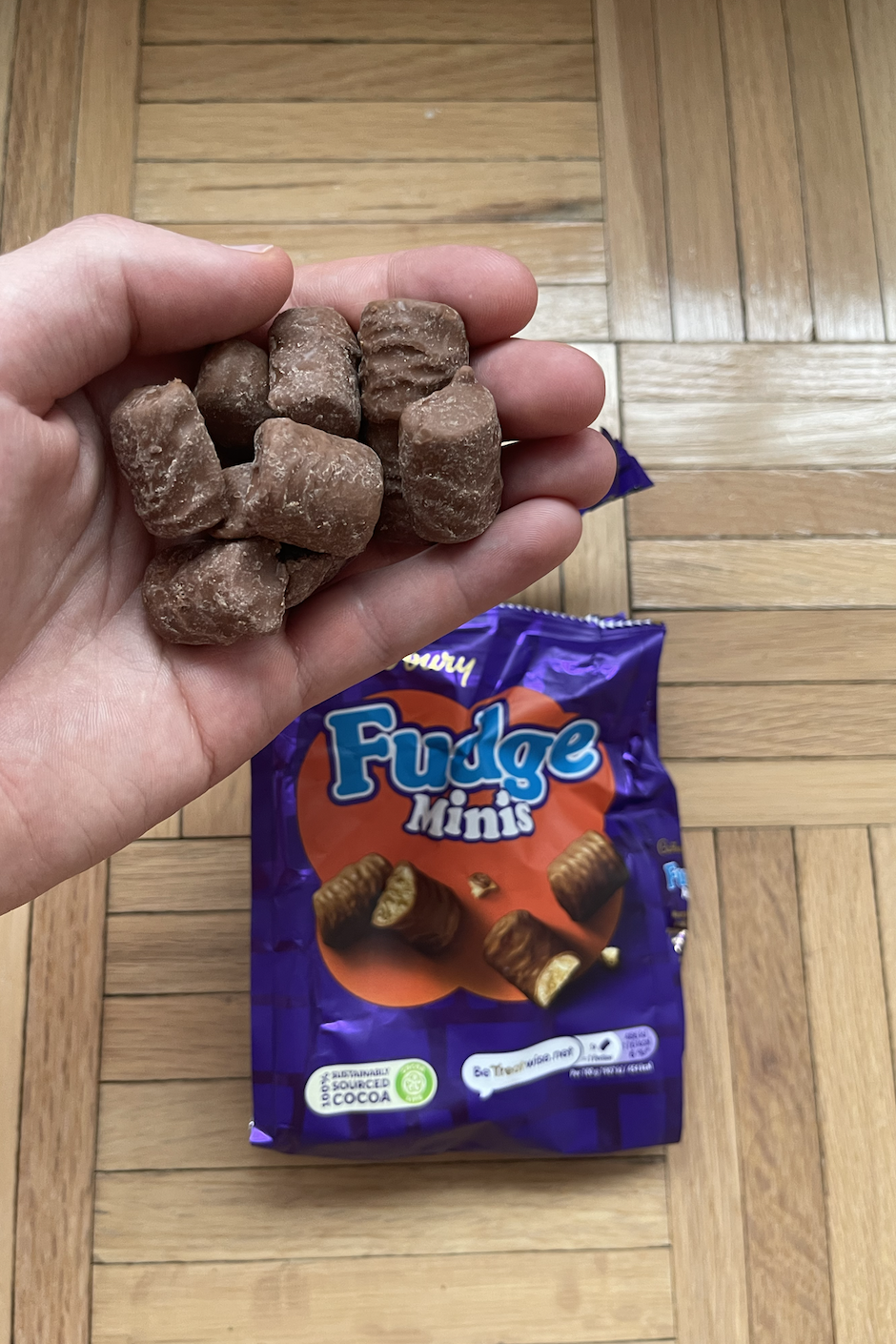 Hand holding chocolate fudge mints above an opened package of the same candy