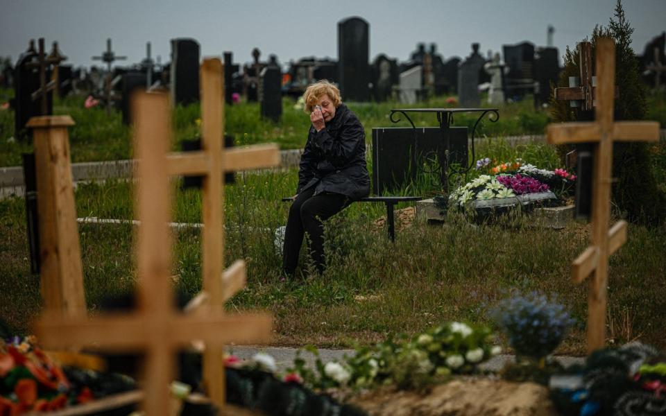 A woman mourns while visiting the grave of Stanislav Hvostov, 22, a Ukrainian serviceman killed during the Russian invasion of Ukraine. He is buried in the military section of a Kharkiv cemetery in Bezlioudivka, eastern Ukraine - DIMITAR DILKOFF/AFP