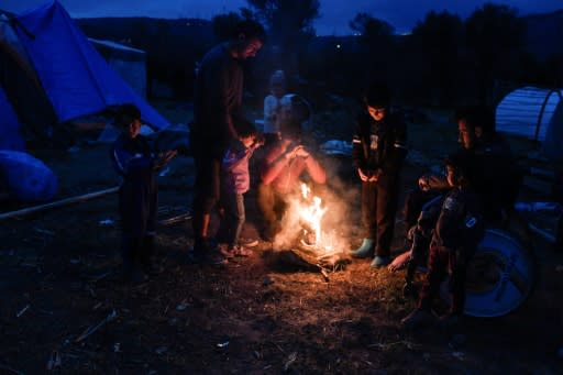 Migrants light a fire in their makeshift camp on Chios island