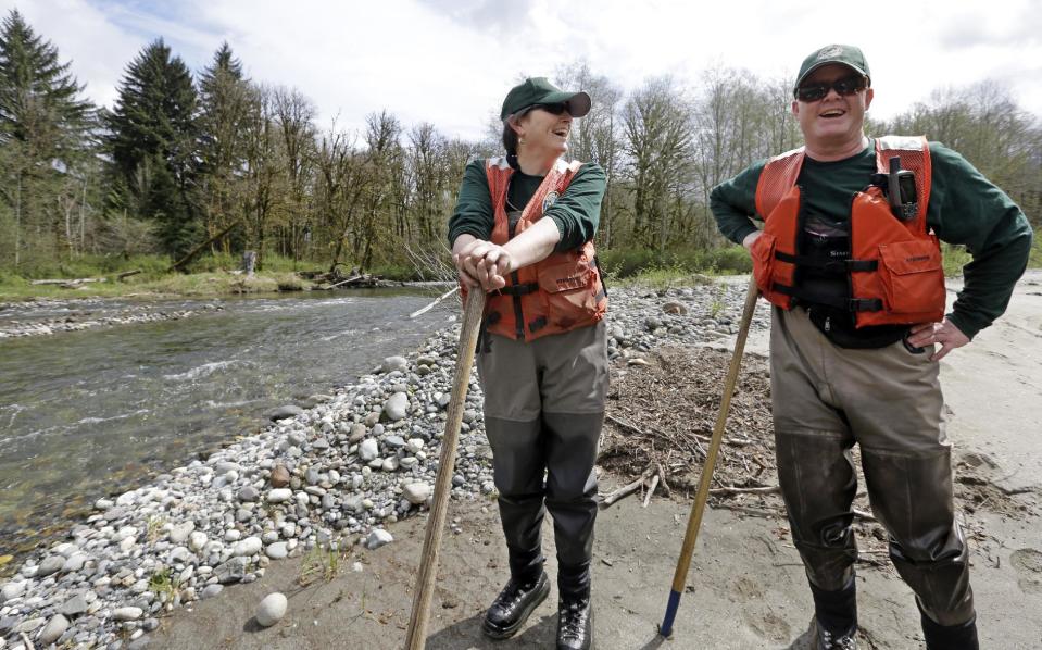 In this photo taken Tuesday, April 15, 2014, fisheries biologists Jenni Whitney, left, and Pete Verhey take a brief break after wading through Squire Creek, a tributary of the North Fork of the Stillaguamish River, while searching for salmon spawning nests near Darrington, Wash. Finding the nest, called a redd, is an encouraging sign that steelhead trout may be making their way upstream from Oso., Wash., above where a massive landslide decimated a riverside neighborhood a month ago and pushed several football fields worth of sediment down the hillside and across the river. As search crews continue to look for people missing in the slide, scientists also are closely monitoring how the slide is affecting federally endangered fish runs, including Chinook salmon and steelhead. (AP Photo/Elaine Thompson)