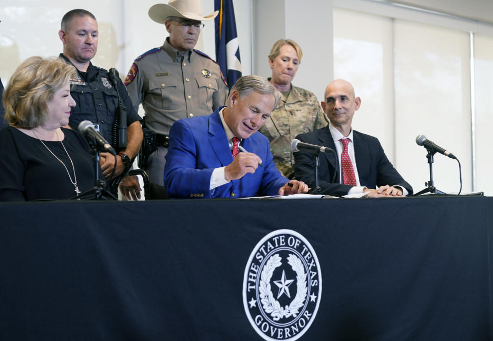 FILE - Texas Gov. Greg Abbott, front center, is flanked by state Sen. Jane Nelson, R-Flower Mound, front left, and Rep. Greg Bonnen, R-Friendswood, front right, with others looking on as he signs a bill that provides additional funding for security at the U.S.-Mexico border on Sept. 17, 2021, in Fort Worth, Texas. Abbott on Tuesday, Dec. 6, 2022, named Nelson, a longtime GOP lawmaker with a record of bipartisan appeal, as his choice to become the state's new election chief after facing blowback and scrutiny over his past picks to oversee voting. (AP Photo/LM Otero, File)