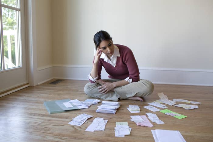 A woman looking at her bills arranged on the floor