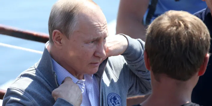 Putin in gray top adjusting collar