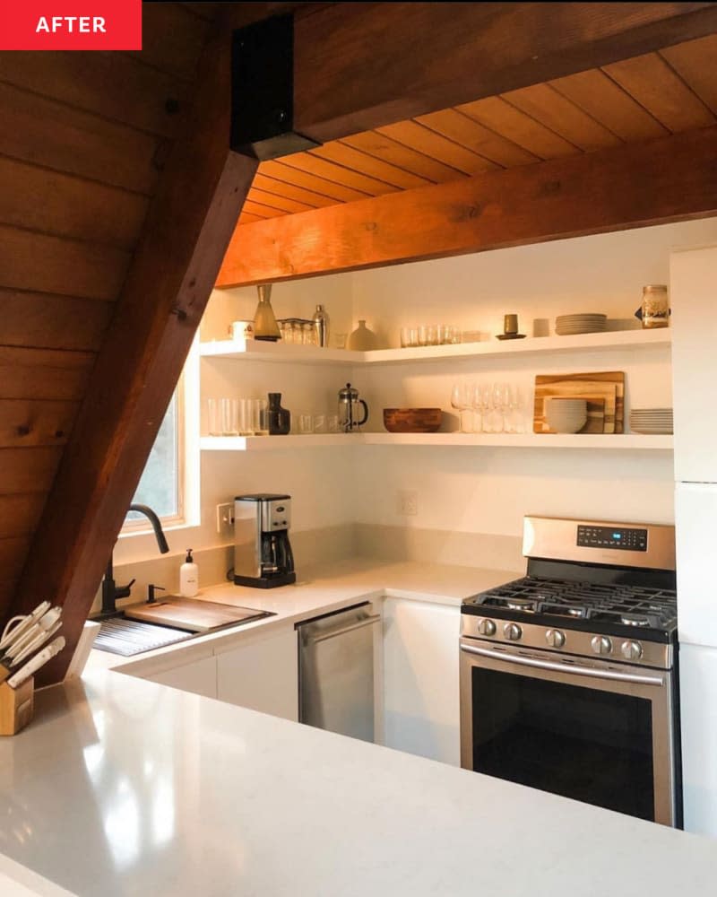 A-frame kitchen after renovation: white cabinets, white walls, open white shelves, pale gray countertops