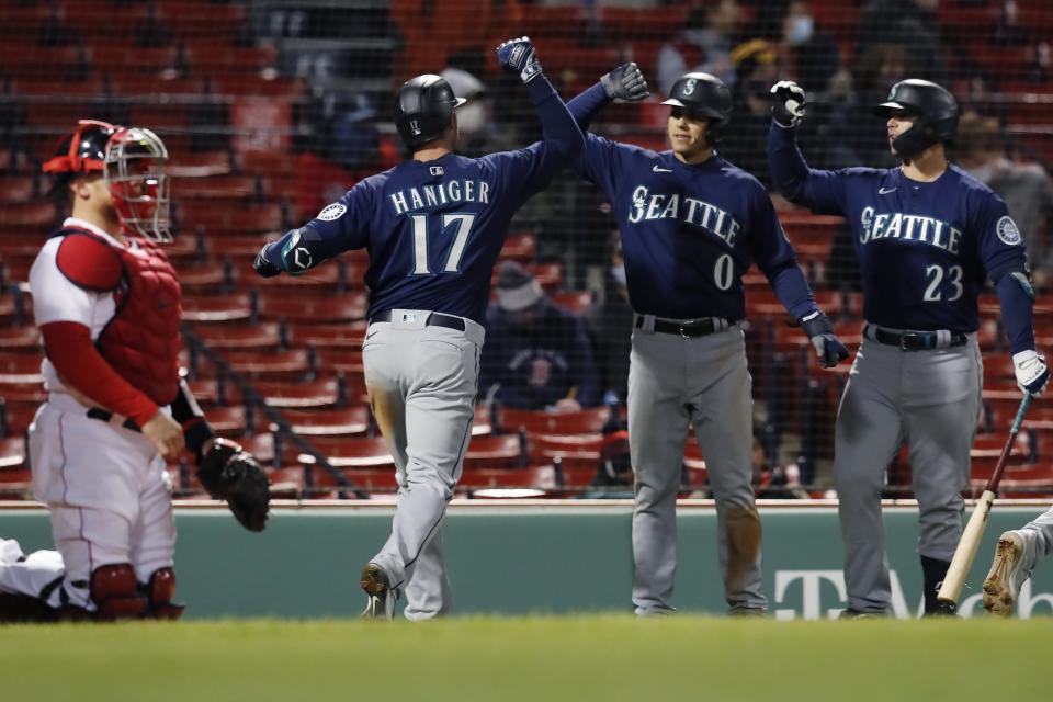 Boston Red Sox's Christian Vazquez, left, kneels at home plate as Seattle Mariners' Mitch Haniger (17) celebrates his three-run home run that also drove in Sam Haggerty (0) during the 10th inning of a baseball game, Thursday, April 22, 2021, in Boston. (AP Photo/Michael Dwyer)