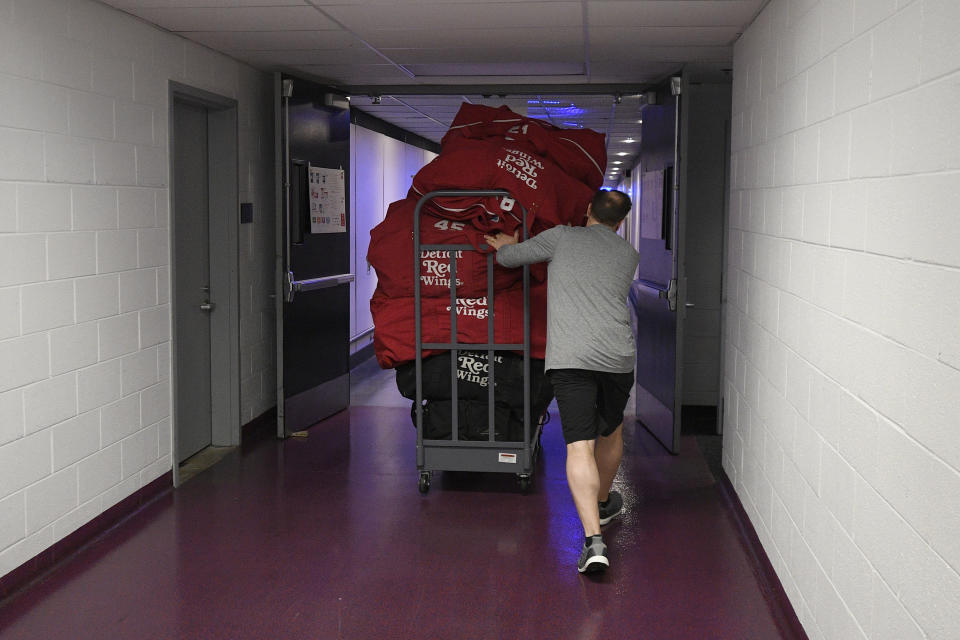 Paul Boyer, head equipment manager of The Detroit Red Wings NHL hockey team, wheels out equipment bags in the hallway of Capital One Arena, Thursday, March 12, 2020, in Washington. The Washington Capitals were to host the Red Wings Thursday evening until the league, following the NBA’s lead, suspended the season Thursday amid the coronavirus outbreak. (AP Photo/Nick Wass)