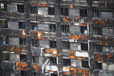 FILE PHOTO: Workers stand inside the burnt out remains of the Grenfell tower in London, Britain, October 16, 2017. REUTERS/Hannah Mckay/File Photo