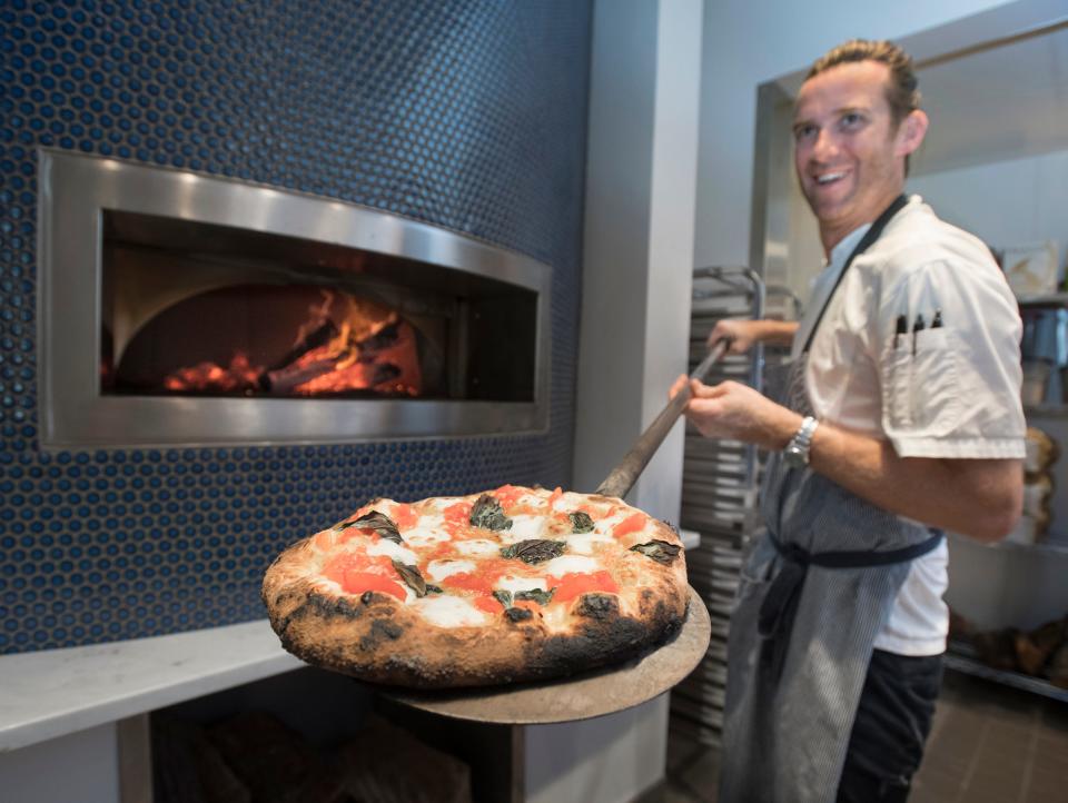 Executive Chef James Briscione removes a Pizza Margherita from the woodfire oven at the new Angelena's Ristorante Italiano in downtown Pensacola on Thursday, June 27, 2019.