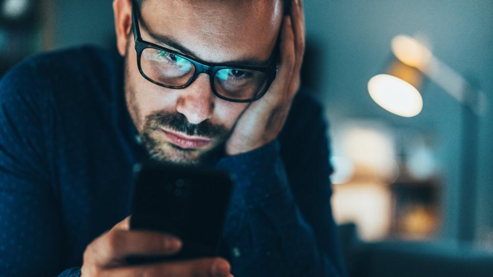 Young man addicted to social media texting in the dusk at home.